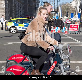 Ein Paar, das den Fahrradverleih in London benutzte. Hier in Westminster, im Zentrum von London. Das Leihfahrrad, das mehr umweltfreundlichen Verkehr fördert, wurde 2010 eingeführt; die Barclays Bank war der erste Sponsor und Santander ab 2015. Obwohl es nach dem damaligen Bürgermeister von London allgemein als „Boris Bikes“ bekannt war, wurde das Konzept zunächst vom früheren Bürgermeister, Ken Livingtone, promotet. Stockfoto