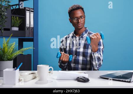 Fit und sportlich Mann macht Fitness-Training Übung für steife Muskeln. Aktive selbstbewusste und starke junge Erwachsene Hanteln heben, um in Form zu bleiben, während der Arbeit im Büro. Stockfoto