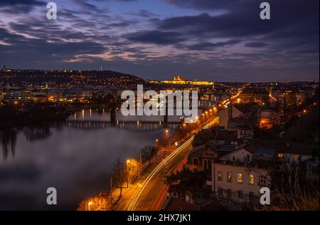 Verträumte Nachtansicht der Moldau mit magischem Himmel und Lichtern von Straßen und Brücken bei Sonnenuntergang hinter der Prager Burg in der Prager Altstadt. Stockfoto