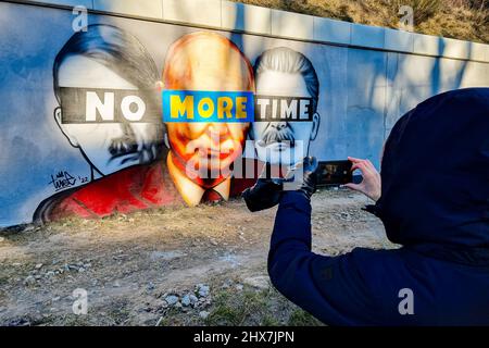 Danzig, Polen. 10. März 2022. Ein Wandgemälde von Putin, Hitler und Stalin mit dem Slogan „No More Time“ ist an der Wand neben dem Bahnhof Danzig-Jasien der PKM zu sehen. Die erste einer Serie von Wandgemälden gegen den Krieg mit dem Titel „Solidarität mit der Ukraine“ wurde erstellt. Der Autor ist Tuse, einer der bekanntesten Straßenkünstler in Polen. Es ist eine gemeinsame Initiative der Woiwodschaft Pommern, der Pommerschen Stadtbahn und der Akademie der Schönen Künste in Danzig. Kredit: SOPA Images Limited/Alamy Live Nachrichten Stockfoto