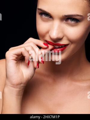 Zerreißendes Rot. Eine junge Frau mit roten Lippen und Nägeln. Stockfoto