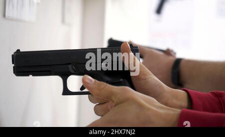 Der Ausbilder lehrt einen Mann, eine Waffe oder Waffe zu handhaben. Nahaufnahme der männlichen Hände mit Pistole beim Training mit dem Instruktor. Nahaufnahme des Nachladens von Menschenhand Stockfoto