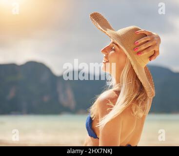 Genießen Sie die Sonne. Aufnahme einer glücklichen jungen Frau in einem Bikini, der sich an einem tropischen Strand entspannt. Stockfoto