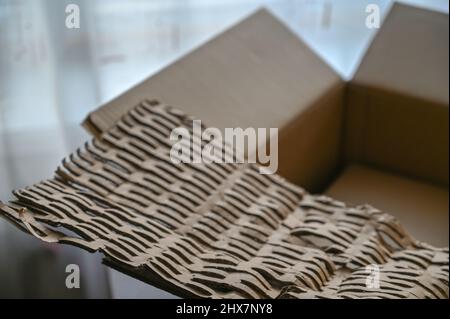 Leeren Sie den Paketkasten und den Schutzfüller. Umweltfreundliche Füllanlage aus recyceltem Karton. In Innenräumen. Frontfokus. Stockfoto