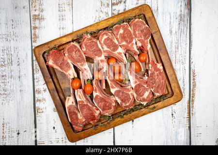 Lammkoteletts auf Holzhintergrund. Rohe Lammkoteletts auf Holzdielett. Draufsicht Stockfoto