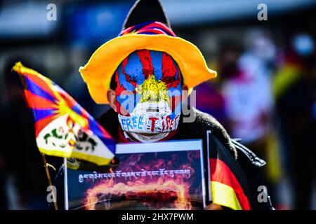 Berlin, Deutschland. 10. März 2022. Ein Mann mit Maske nimmt an der Demonstration des Verbands der Tibeter in Deutschland (VTD) "Solidarität für Tibet und Protest für den Frieden" am Alexanderplatz Teil. Jedes Jahr am 10. März gedenken Tibeter auf der ganzen Welt des Aufstands des tibetischen Volkes vom 10. März 1959, der von chinesischen Truppen blutig niedergeschlagen wurde und als Folge dessen der Dalai Lama aus Tibet fliehen musste. Quelle: Fabian Sommer/dpa/Alamy Live News Stockfoto