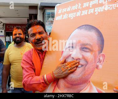 Bhopal, Indien. 10. März 2022. Ein Mitarbeiter der Bharatiya Janata Partei trägt Farbe auf ein Plakat des Hauptministers von Uttar Pradesh Yogi Adityanath, um die Führung der BJP in den Wahlen zur Nationalversammlung von Uttar Pradesh, Manipur, Goa und Uttarakhand zu feiern. Die Stimmen werden nach den Parlamentswahlen in fünf Staaten gezählt, von denen die BJP in vier Staaten mit Ausnahme von Punjab führend ist. Kredit: SOPA Images Limited/Alamy Live Nachrichten Stockfoto