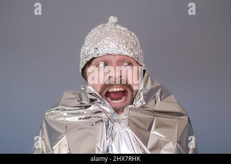 Junger Mann in einer Folienkappe, der Angst und Stress hat. Stockfoto