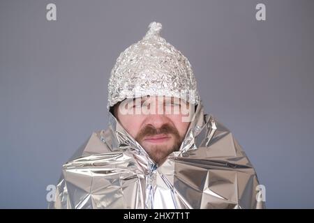 Junger Mann in einer Folienkappe, der Angst und Stress hat. Stockfoto