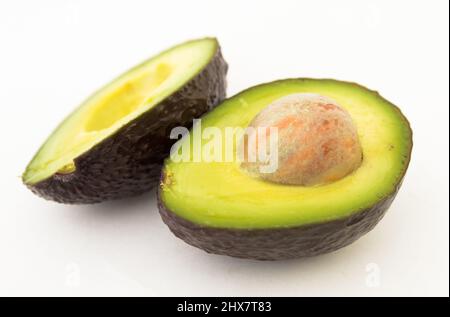 Halbierte Avocado mit Knochen auf weißem Hintergrund Stockfoto