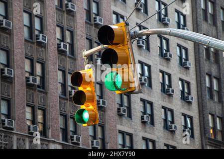 Gelbe Ampel mit grünem Licht im Hintergrund eines Hochhauses Stockfoto