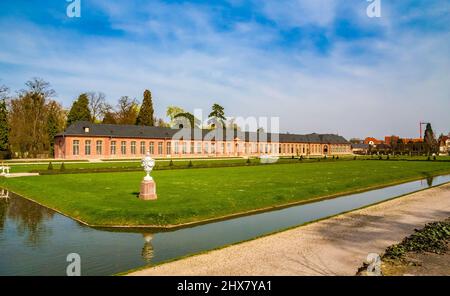 Schöner Panoramablick auf das Orangeriereparterre mit dem Orangerie-Gebäude, umgeben von einem Wasserkanal, im Garten des berühmten Schwetzinger... Stockfoto