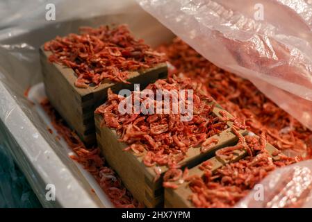 Kleine getrocknete Garnelen in einem Holzmasu-Messwürfel auf einem asiatischen Nassmarkt. Stockfoto