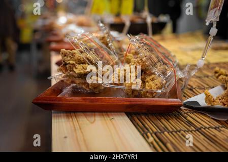 Karaage oder japanisches gebratenes Huhn wird in einem Plastikbehälter verpackt und zum Verkauf - japanisches Street Food. Stockfoto