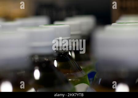 Eine Reihe von Tee-Plastikflaschen mit weißen Plastikkappen in einem Lebensmittelgeschäft. Stockfoto