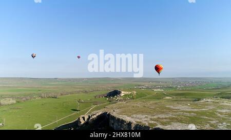 Heißluftballons am Himmel über dem Feld auf dem Land. Aufnahme. Luftaufnahme der Luftaufnahmen über der Sommerwiese. Stockfoto