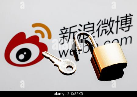 Ein offenes Sicherheitsschloss und Schlüssel auf dem Hintergrund des chinesischen Microblogging-Service-Logos von Weibo in Spiegelreflexion. Stockfoto