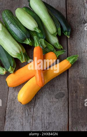 Ein Satz von bunten Zucchini gelb, grün, weiß, orange auf dem Tisch close-up. Hintergrund der Speisen. Frisch geerntete Zucchini, zugeschnittenes Sommerkürbis. Gepflückte grüne Zucchini. Stillleben in der Küche. Stockfoto