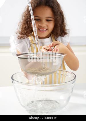 Pfeffer- und Quinoa-Salat - Quinoa in einem Sieb spülen (Schritt 2 von 6) Stockfoto
