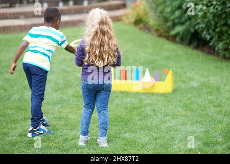 Kinder spielen im Garten mit Pappring werfen Spiel Stockfoto