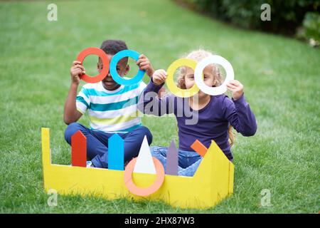 Kinder spielen im Garten mit Pappring werfen Spiel Stockfoto