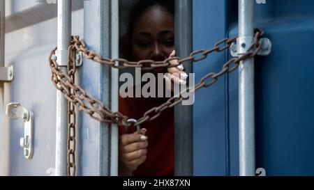 Frau, die im Frachtcontainer gefangen ist, wartet auf Menschenhandel oder Vorarbeiter, Frau mit Hauptschlüssel wartet auf Hilfe von Holp Stockfoto