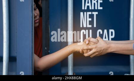 Frau, die im Frachtcontainer gefangen ist, wartet auf Menschenhandel oder Vorarbeiter, Frau mit Hauptschlüssel wartet auf Hilfe von Holp Stockfoto