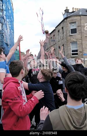 Jedburgh, Donnerstag, 10. März 2022. Jugendliche fordern die „bejubelte“ „Ba“ während der jährlichen „Fastern Eve Handba“-Veranstaltung in der High Street in den Scottish Borders von Jedburgh am 10. März 2022 in Jedburgh, Schottland. Die jährliche Veranstaltung, die im 18. Jahrhundert begann, findet heute statt und umfasst zwei Teams, die Uppies (Bewohner aus dem oberen Teil von Jedburgh) und die Doonies (Bewohner aus dem unteren Teil von Jedburgh), die den Ball entweder auf den oberen oder unteren Rand der Stadt bringen. Der Ball, der aus Leder besteht, mit Stroh gefüllt und mit Bändern verziert ist, wird in die Menge geworfen, um das Spiel zu beginnen. ( Stockfoto