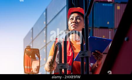 Weibliche Vorarbeiter bleiben auf Heben Container Fracht Gabelstapler prüfen oder überprüfen und kontrollieren Gabelstapler Konzept Service und Transport logistic. Stockfoto