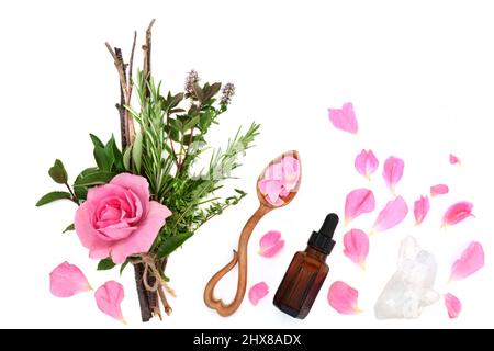 Zaubertrank Zubereitung mit Hexenbündel aus Kräutern und Rosenblüten, Liebeslöffel mit Blütenblättern, Flasche mit ätherischem Öl, Quarzkristall. Stockfoto