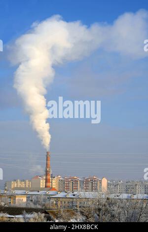 Kommunaler Kesselraum raucht im Wohngebiet der Stadt an einem sonnigen Tag im Winter. Stockfoto