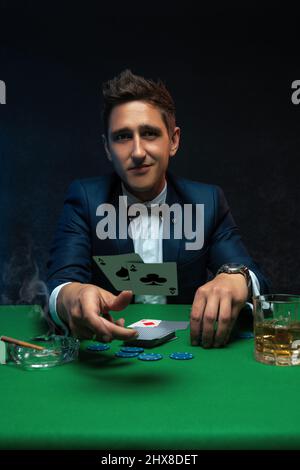 Glücklicher Pokerspieler, der ein Paar Asse an den grünen Tisch im Casino wirft. Stockfoto
