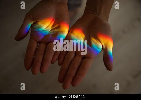 Regenbogenstrahl auf der Hand einer Frau. Stockfoto