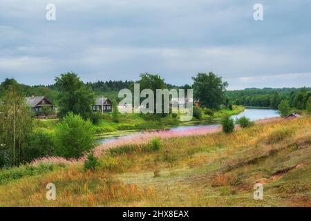 Das alte Dorf Saminsky Pogost mit Holzhäusern am Ufer des Flusses. Nordsommer auf dem Land. Region Wologda, Russland Stockfoto