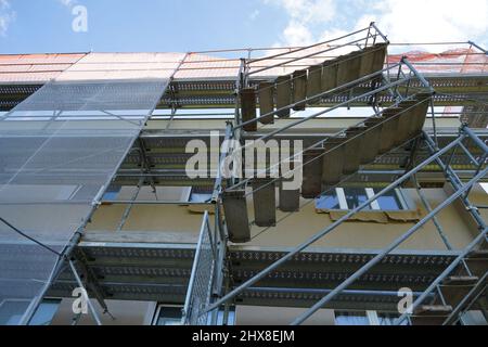 Gerüst und Schutznetz an einer Hausfassade. Low-Angle-Ansicht. Ausschnitt einer Rekonstruktion des Hauses. Stockfoto