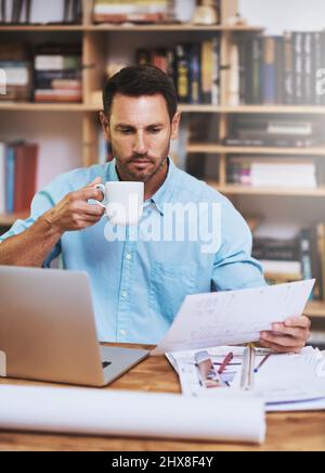 Die harte Arbeit zu Hause erledigen. Eine kurze Aufnahme eines Geschäftsmannes, der zu Hause ein paar Papierkram las. Stockfoto