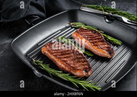 Gegrilltes Top-Lendenrindsteak oder brasilianisches Picanha, gebratenes Fleisch auf der Grillpfanne. Schwarzer Hintergrund. Draufsicht Stockfoto