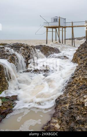 Meereswellen brechen Felsen an der französischen Atlantikküste mit Angelhütte in der Nähe von La Rochelle, Charente Maritime, Frankreich Stockfoto
