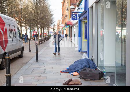 Worcester City Centre, Großbritannien - Person schläft rauh auf der Straße, früh morgens, wenn Leute vorbeigehen. Stockfoto