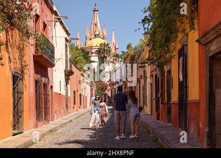Mexiko, Guanajuato, San Miguel de Allende, eine Straße in der Stadt mit typischen Häusern und Geschäften, die in die Stadt mit Parroquia de San Miguel Arcángel führen Stockfoto