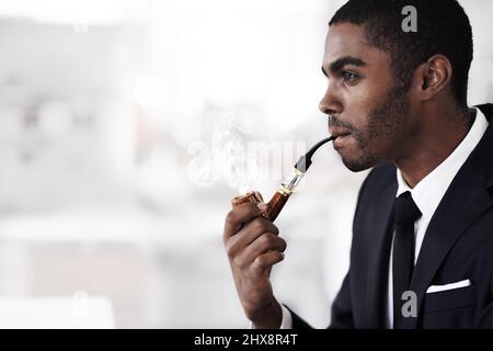 Stilvolles Dampfen. Ein junger Geschäftsmann, der in einem Büro eine elektronische Pfeife raucht. Stockfoto