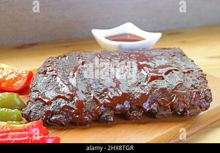 Nahaufnahme von leckeren BBQ Schweinestrippen mit gegrilltem auf einem Schneidebrill Stockfoto