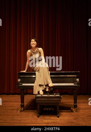 Shes bereit, die Menge zu gefallen. Aufnahme einer jungen Frau, die am Ende eines Musikkonzerts auf ihrem Klavier sitzt. Stockfoto