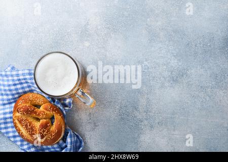 Bayerische Brezeln und ein Glas Lagerbier. Oktoberfest-Speisekarte, traditionelle gesalzene Brezeln auf hellgrauem Hintergrund. Draufsicht mit Platz für Text. Stockfoto