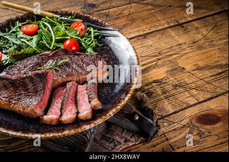 BBQ gegrillte Tasse Rumpsteak auf dem Teller mit Gemüsesalat. Holzhintergrund. Draufsicht. Speicherplatz kopieren Stockfoto