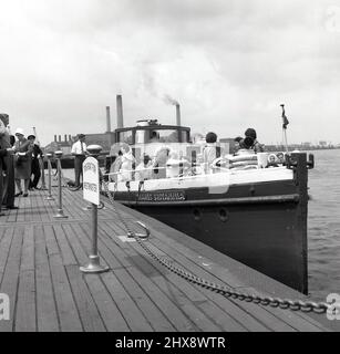 1960s, historisch, Greenwich, Southeast London, ein dampfbetriebenes Vergnügungsboot, Thames Britannia mit Passagieren, moore am Pier. Auf dem Schild auf dem Holzsteg steht: „Dieses Boot für Westminster“. Die Schornsteine des kohlebefeuerten Greenwich-Kraftwerks im Hintergrund. Stockfoto
