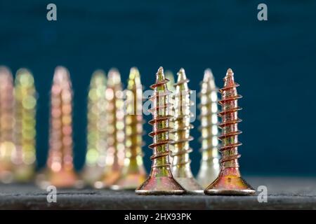 Die Gruppe der selbstschneidenden Schrauben wird vor farbigem Hintergrund angezeigt. Diese Schrauben haben flache Köpfe. Stockfoto