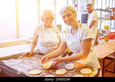 Das Team der Bäckerei arbeitet zusammen, um Auszubildende im Handwerk auszubilden Stockfoto