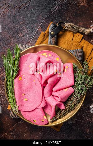 Salami-Scheiben mit Pistazien-Nüssen in Stahlplatte mit Thymian und Rosmarin. Dunkler Hintergrund. Draufsicht Stockfoto