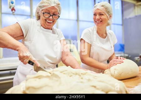 Die junge Bäckerlehrling hilft beim Kneten und Schneiden von Teig im Bäckereigeschäft der Familie Stockfoto